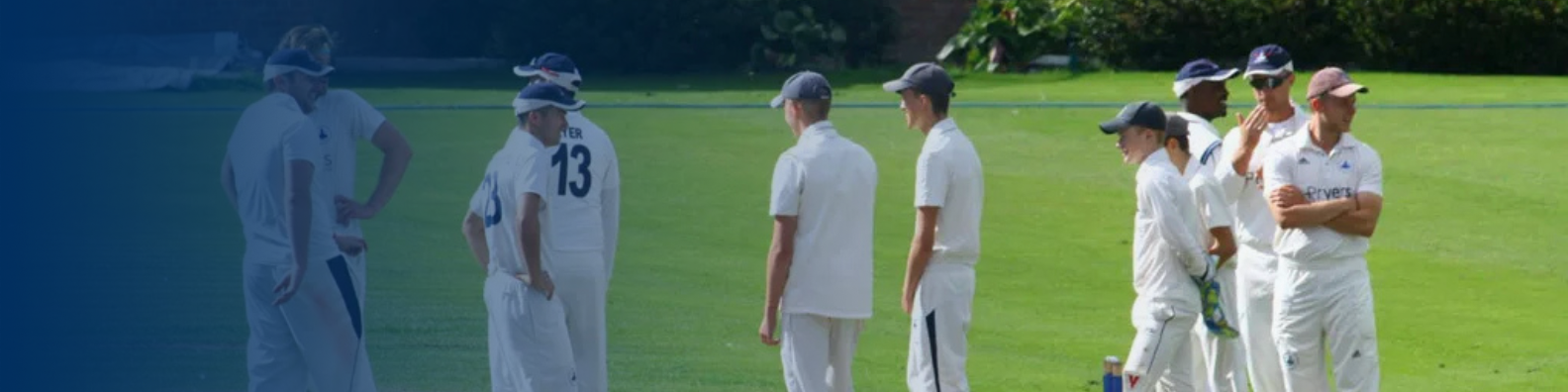 CRICKET - image shows team of cricket players on the pitch chatting.